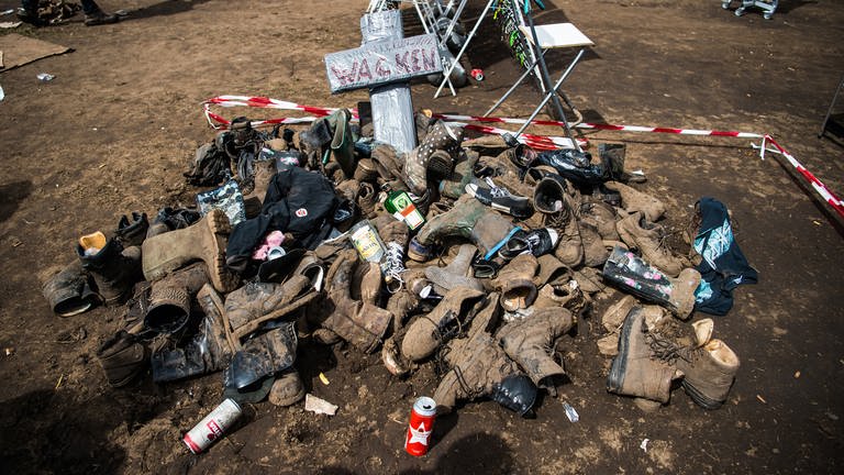 Kaputte und verschlammte Schuhe auf einem Haufen mit Kreuz und leeren Flaschen (Wacken) (Foto: dpa Bildfunk, Christophe Gateau)
