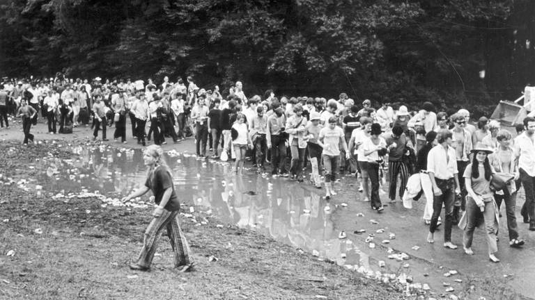 Woodstock Festivalbesucher waten durch Wasser und Müll