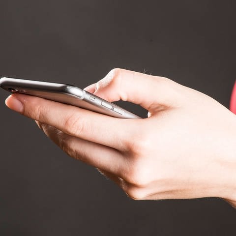 Woman holding a smartphone in her hand. Symbolfoto