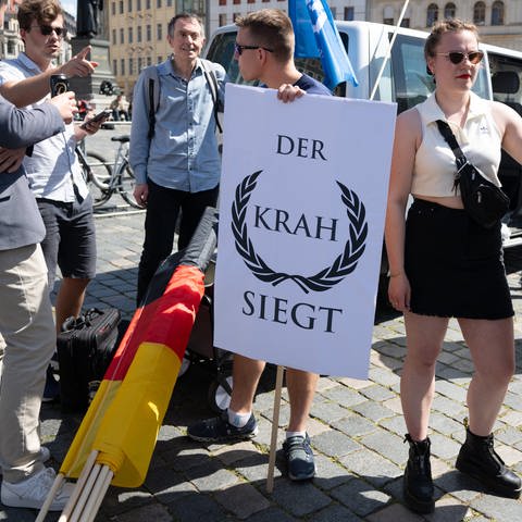 Mitglieder der AfD-Jugendorganisation Junge Alternative halten auf einer AfD-Wahlkampfveranstaltung auf dem Neumarkt verschiedene Schilder für den AfD-Spitzenkandidat für die Europawahl Krah.