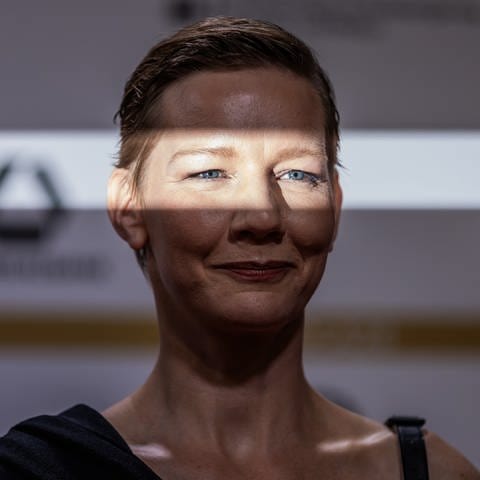 Sandra Hüller mit einem Lichstreifen im Gesicht, sodass nur ihrer Augen zu sehen sind