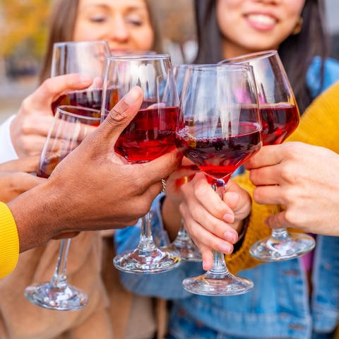 Nahaufnahme von Freunden, die auf einer Straße in der Stadt feiern und mit Wein anstoßen