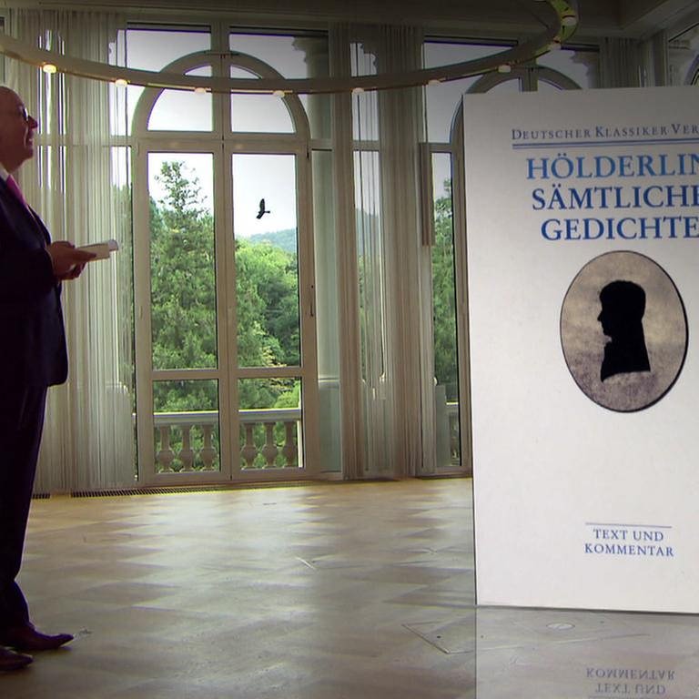 Denis Scheck steht neben dem Buch "Sämtliche Gedichte" von Friedrich Hölderlin (Foto: SWR, SWR -)