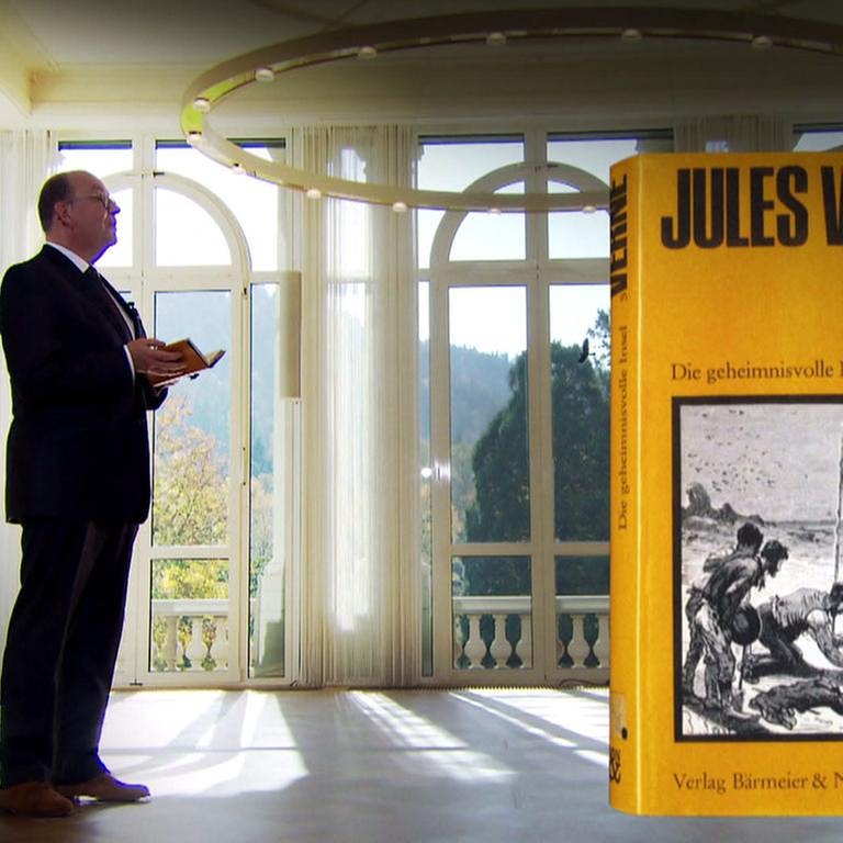 Denis Scheck und daneben das Buch "Die geheimnisvolle Insel" von Jules Verne