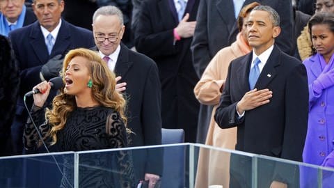Queen Bey und President Barack: Als Obama für seine zweite Amtszeit eingeschworen wird, singt Beyoncé die Nationalhymne: Im Vordergrund eine Frau im schwarzen Kleid, die singt, im Hintergrund steht Barack Obama im Mantel und legt die Hand aufs Herz. (Foto: IMAGO, IMAGO / UPI Photo)