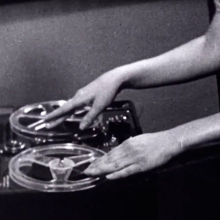 Schwarz-weiß Bild: Frauenhände bedienen ein Tonbandgerät