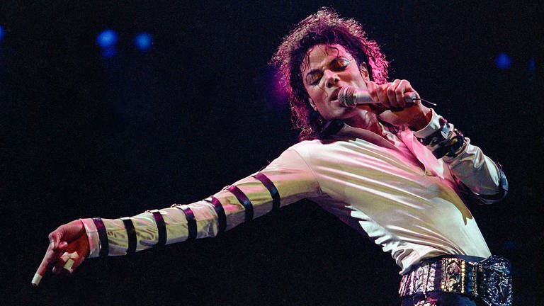Michael Jackson in einem weiß-glänzenden Oberteil beim Singen auf einer Bühne (Foto: picture-alliance / Reportdienste, picture alliance / ASSOCIATED PRESS)