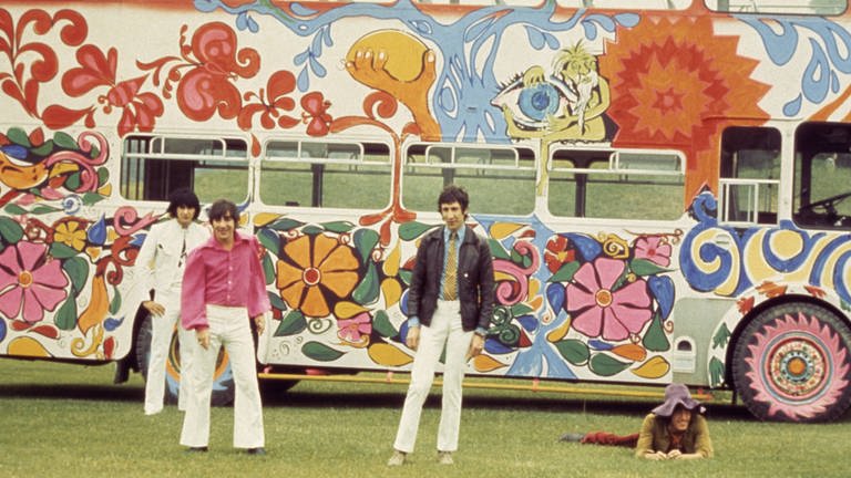 Junge Männer stehen vor einem buntem Hippiebus