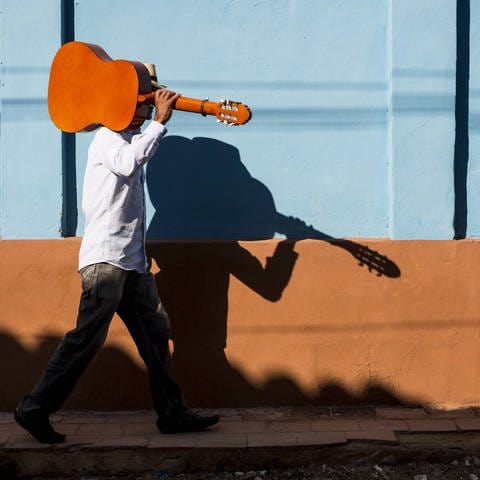 Mann unterwegs mit einer Gitarre auf der Schulter (Foto: IMAGO, IMAGO / Westend61)