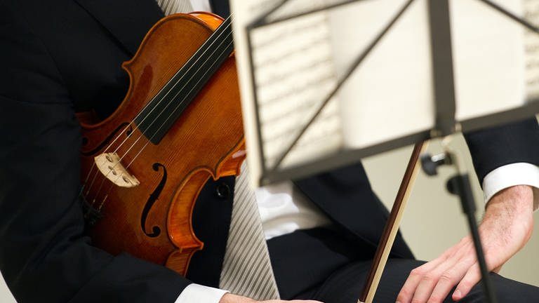 Ein Geiger sitzt mit seiner Violine hinter einem Notenständer. (Foto: picture-alliance / Reportdienste, picture alliance / dpa | Arno Burgi)