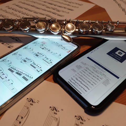 Begleit-Apps für Musiker*innen: Auf einem Tisch liegen zwei Smartphones, eine Querflöte und Notenblätter