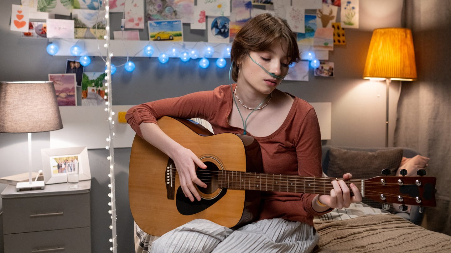Symbolbild: Eine Teenagerin musiziert in einem Krankenhausbett (Foto: IMAGO, IMAGO / Pond5 Images)
