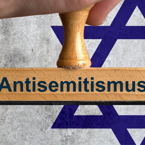 Stempel mit der Aufschrift "Antsemitismus" vor einer jüdischen Flagge
