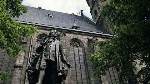 Bach-Denkmal vor Sankt Thomas in Leipzig. Im Hintergrund die Kirche.