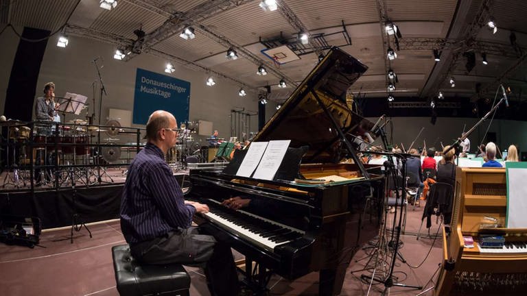 Mann sitzt am Flügel bei Proben mit dem Orchester zum Eröffnungskonzert (Foto: SWR, Ralf Brunner)