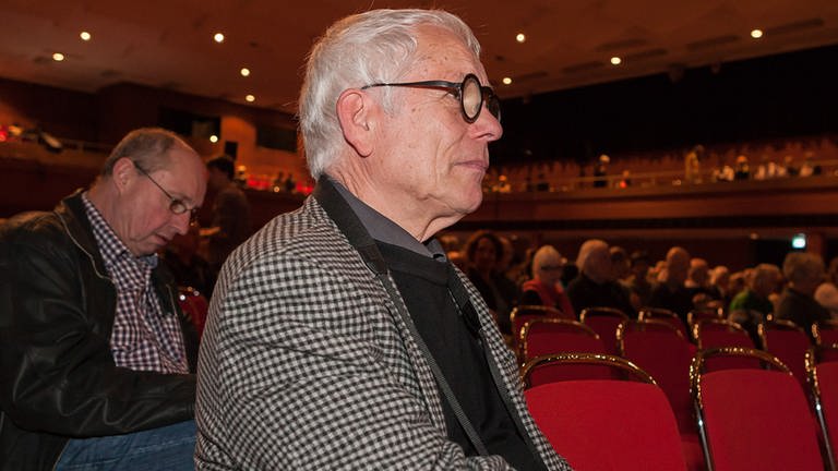 Mann mit Brille und kariertem Jackett sitzt im Konzertsaal