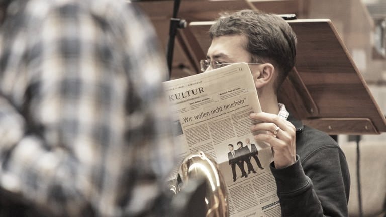 Mann sitzt im Orchester und liest Zeitung (Foto: SWR, Tilman Stamer)