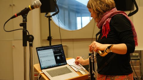 Frau mit Bassklarinette vor Notenpult mit Laptob darauf (Foto: SWR)