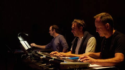 Drei Männer konzentriert an der Klangregie
