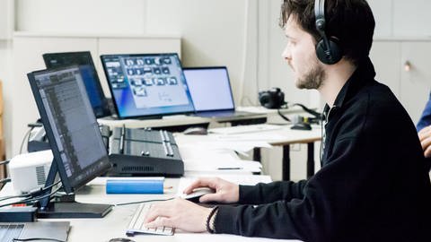 Mann mit Kopfhöhrer sitz vor dem PC-Bildschirm und programmiert. (Foto: SWR, Anja Thölking)
