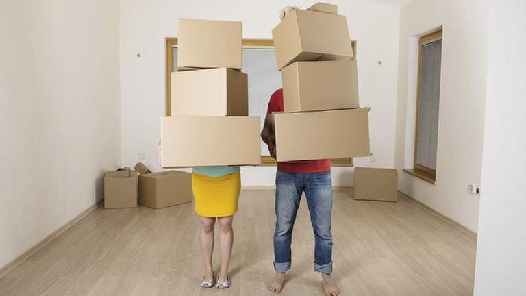 Ein Paar steht in einer Wohnung mit Umzugskisten in den Händen (Foto: Getty Images, Thinkstock -)
