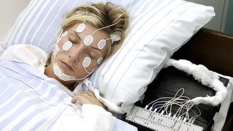 Frau mit Elektroden am Kopf in einem Schlaflabor