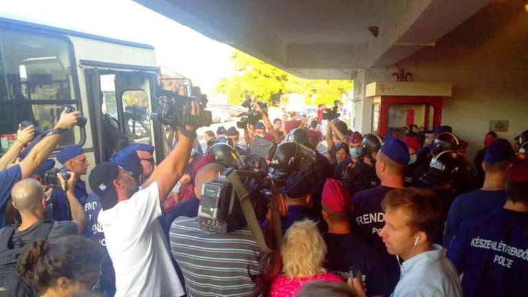 Bereitschaftspolizisten bringen Flüchtlinge zum Weitertransport in den Bus (Foto: SWR, SWR - Anna Frenyo)