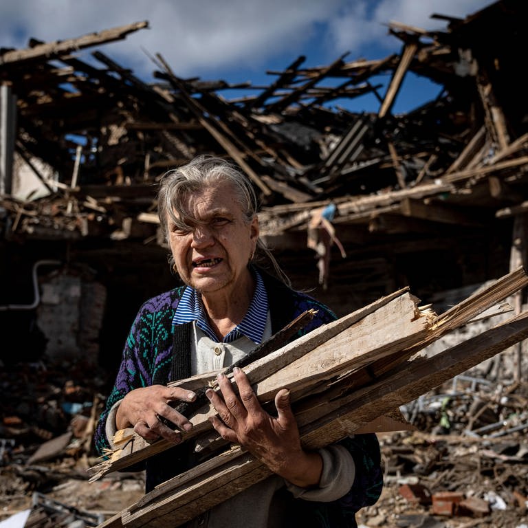 Eine ältere Frau räumt die Trümmer eines im Krieg zerstörten Hauses in der Ukraine auf (Foto: picture-alliance / Reportdienste, picture alliance / ASSOCIATED PRESS | Evgeniy Maloletka)