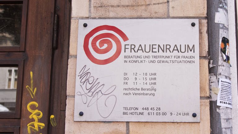 Schild an einer Hauswand mit der Aufschrift "Frauenraum": Beratung und Treffpunkt für Frauen in Konflikt- und Gewaltsituationen in Berlin