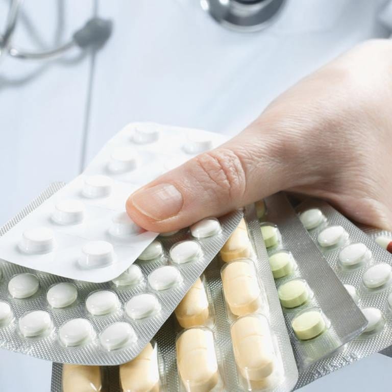 Ein Arzt hält mehrere Tablettenpackungen in der Hand.