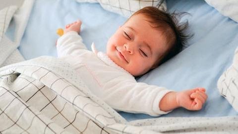 Ein Baby lächelt im Schlaf.