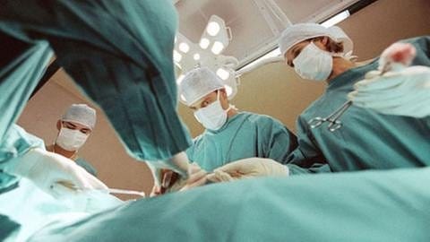 Ärzte mit Kitteln und Mundschutz während einer Operation (Foto: Getty Images, Thinkstock -)