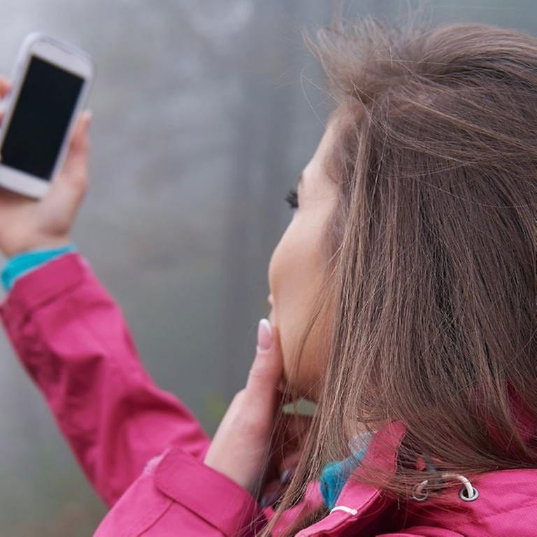 Eine Frau sucht mit ihrem Handy nach einem Signal