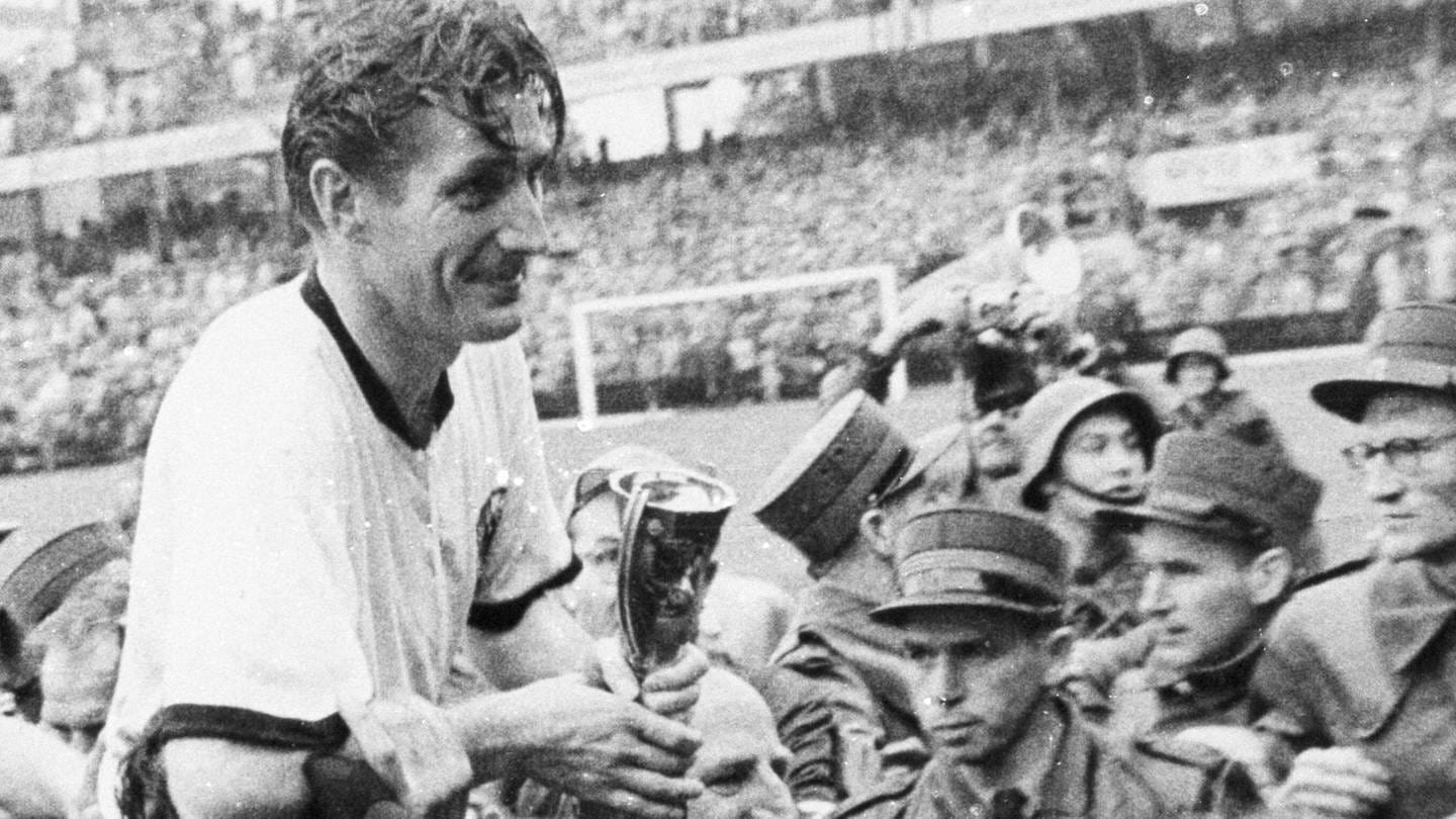 Kapitän Fritz Walter lässt sich nach dem Sieg bei der Fußball-WM in Bern mit Coupe Jules Rimet auf Schultern tragen, dahinter Horst Eckel (Foto: IMAGO, imago images / Pressefoto Baumann)