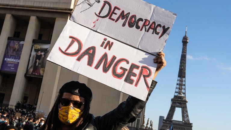 Plakat mit der Aufschrift "Democracy in danger", daneben der Eiffelturm: Demonstration gegen das globale Sicherheitsgesetz am 21. November 2020 in Paris  Frankreich (Foto: IMAGO, imago images / Hans Lucas)