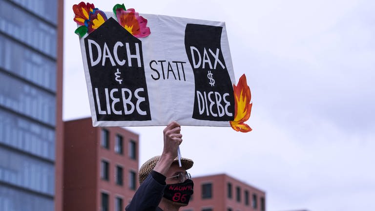 Demonstration für bezahlbaren Wohnraum. Transparent mit der Aufschrift: "Dach und Liebe statt DAX und Diebe"