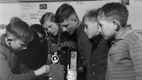 Schüler untersuchen eine Kamera: Nicht nur Filme betrachten, sondern auch die Arbeit mit der "Hardwäre", also der Kamera, gehörte zum Konzept des Unterrichts von Adolf Reichwein  
