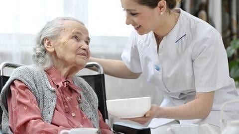 Eine Frau hilft einer alten Frau (Foto: Getty Images, Thinkstock -)