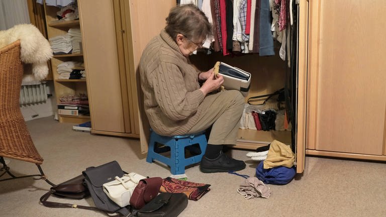 Eine Seniorin räumt den Schrank auf. Döstädning ist ein Aufräum-Trend aus Schweden: vor dem Tod aussortieren und entrümpeln, um den Angehörigen geordnete Verhältnisse zu hinterlassen.