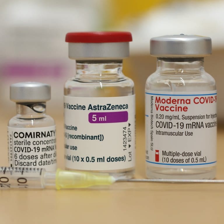 Ampullen mit den Corona-Impfstoffen von Biontech Comirnaty, Astrazeneca und Moderna: Erfolge und Rückschläge bei der Impfstoff- und Medikamenten-Entwicklung haben die Corona-Krise im Jahr 2021 geprägt; vor den Ampullen liegt eine Spritze