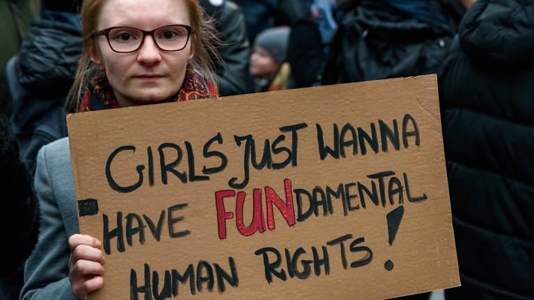 Frau hält Pappschild mit der Aufschrift: "Girls just wanna have FUNdamental Human Rights!": Solidaritäts-Kundgebung 2018 an der Warschauer Brücke in Berlin gegen die Verschärfung der Gesetze in Polen bei Schwangerschaftsabbrüchen  (Foto: IMAGO, IMAGO / snapshot)