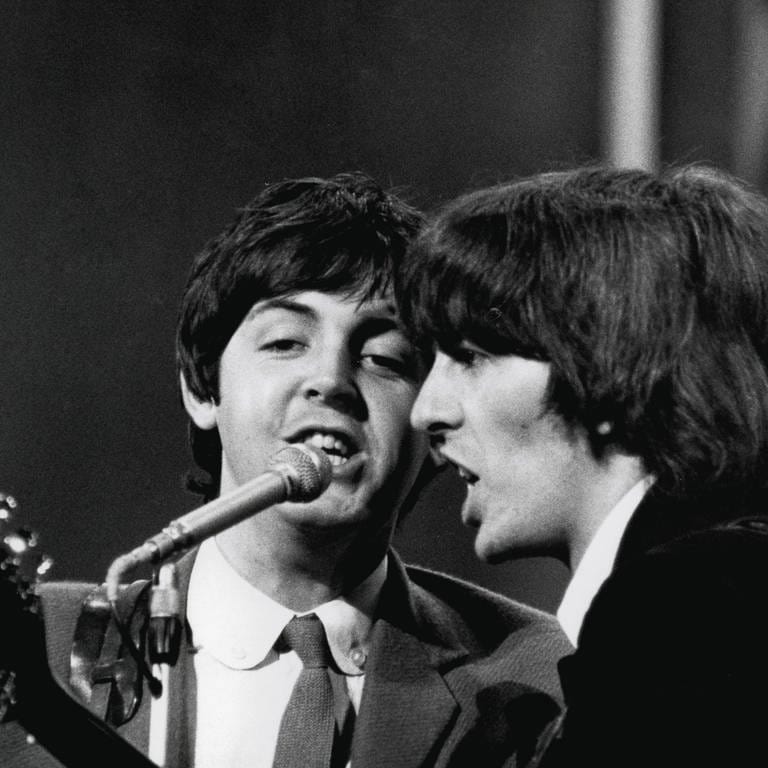 Die beiden Beatles Paul McCartney und George Harrison singen im August 1965