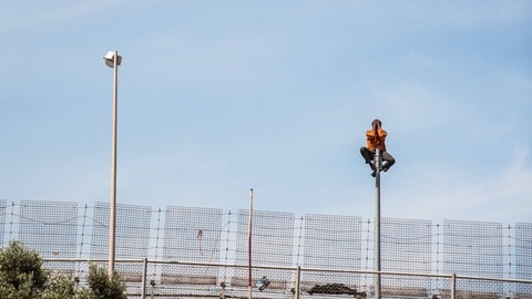 Ein Asylsuchender auf dem Grenzzaun der spanischen Enklave Melilla an der nordafrikanischen Mittelmeerküste. 2014 wurden dort zwei Asylsuchende durch ein Pushback zurückgedrängt. Daraufhin entschied der Europäische Gerichtshof für Menschenrechte, dass Pushbacks unter gewissen Umständen erlaubt sein können. (Foto: IMAGO, IMAGO / Hans Lucas)