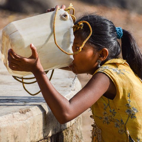 Ein Mädchen, das zu einem trockenen Brunnen gekommen ist, um Trinkwasser zu holen, trinkt Wasser aus einem Kanister. (Foto: IMAGO, IMAGO / NurPhoto)