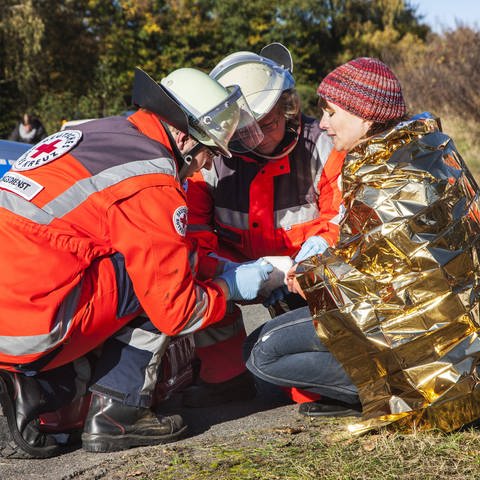 Symbolbild: Frau eingehüllt in eine Rettungsdecke bei einer Notfallübung von verschiedenen Rettungsorganisationen und der Polizei. (Foto: IMAGO, IMAGO / Jochen Tack)