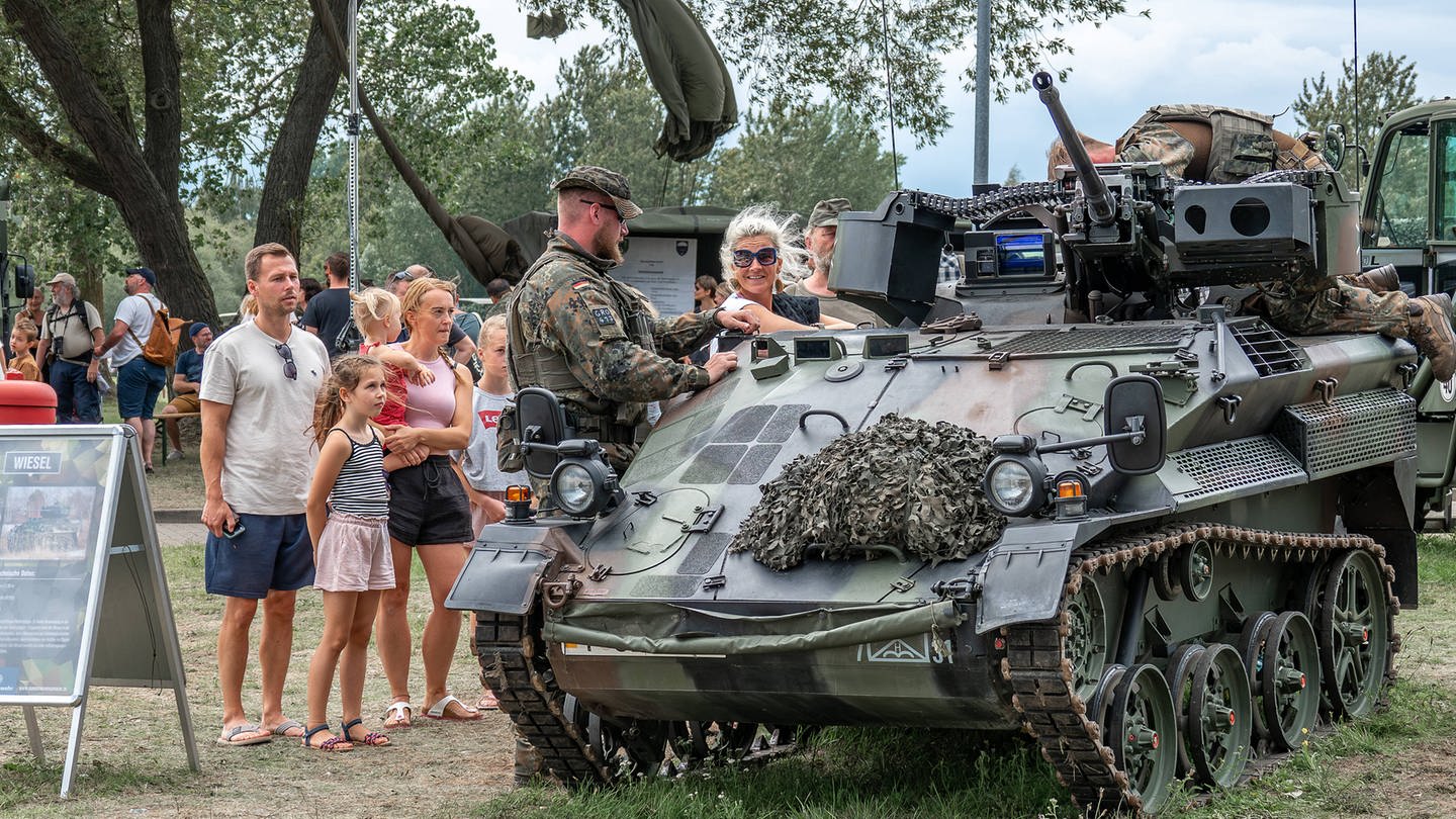 Offener Stützpunkt Hohe Düne in Warnemünde: Eine Familie schaut sich einen Panzer an, ein Bundeswehrsoldat erklärt: Bundesverteidigungsminister Boris Pistorius wünscht sich einen Mentalitätswechsel bei den Deutschen. Sie sollen 