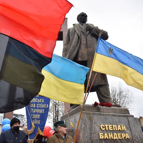 Menschen mit Fahnen in der Nähe des Denkmals für Stepan Bandera in Lwiw während der Feierlichkeiten zu dessen 113. Geburtstag am 1. Januar 2022.