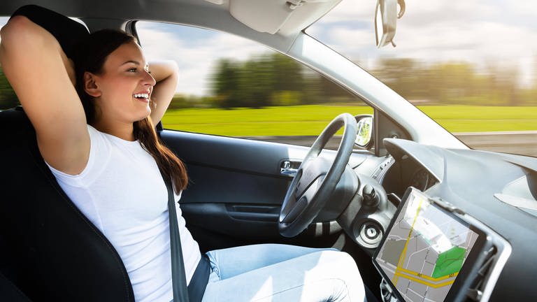 Frau in selbstfahrendem Auto lehnt sich entspannt zurück: Wenn uns in Zukunft ein selbstfahrendes Auto zur Arbeit kutschiert, können wir noch eine Runde ausschlafen.  (Foto: IMAGO, imago images / Panthermedia)