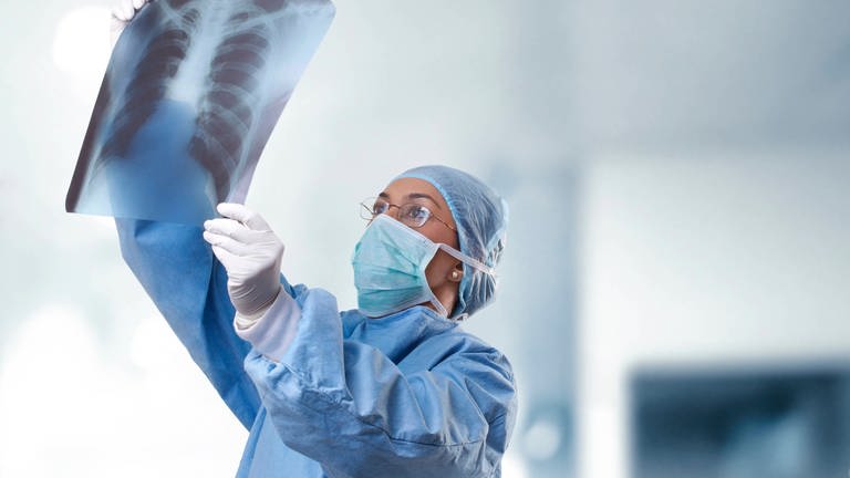 Arzt betrachtet Röntgenbild der Lunge: Long Covid: Kurzatmigkeit und starke Erschöpfung können neben vielen anderen Symptomen Spätfolgen einer Covid-19-Infektion sein. Die Medizin spricht von Long Covid