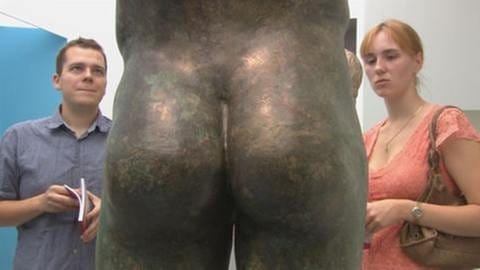Mann und Frau betrachten antike Bronzeskulptur